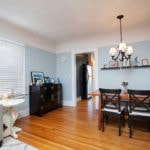 Open living and dining area at 3764 Alabama in North Park featuring hardwood floors, light blue walls, a wood dining table with cross-back chairs, and a dark wood sideboard.