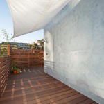 Modern wood deck at 3764 Alabama St in North Park featuring a grey stucco exterior wall, horizontal slat privacy fencing, and a white sun shade sail.