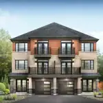 Front exterior of a modern three-story Village Townhome at Empire Avalon with brick cladding, wood-panel accents, and second-story balconies.