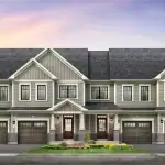 Street-level rendering of luxury townhomes at Empire Riverland, featuring light grey siding, dark shingled roofs, covered entryways, and stone masonry under a soft twilight sky.