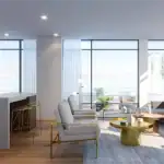 Bright and open-concept suite interior at Distrikt Trailside featuring a contemporary kitchen island, stylish living room seating, and expansive floor-to-ceiling windows.