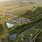 Aerial view of The Heights of Harmony East residential development showing planned rows of modern homes, integrated green spaces, two ponds, and surrounding lush forests under a golden sunset.