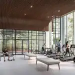 The state-of-the-art fitness center at The Greenwich with floor-to-ceiling windows, modern treadmills, weight lifting equipment, and a unique architectural wood-paneled curved ceiling.