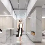 Luxury condo lobby at Nautique Lakefront Residences featuring polished marble floors, a minimalist concierge desk, a modern fireplace, and wood-paneled walls.