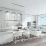 Bright, modern open-concept condo interior at Nautique Lakefront Residences, featuring a white kitchen, dining island, living room, and floor-to-ceiling windows with a lake view.