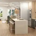 Modern open-concept kitchen at Whitehorn Woods featuring a large waterfall island, light wood cabinetry, grey lower cabinets, and integrated stainless steel appliances.