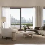 Spacious open-concept living room at The Bedford with floor-to-ceiling glass sliding doors, a curved designer sofa, minimalist decor, and a large terrace overlooking the city.