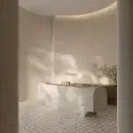 The elegant lobby at The Bedford featuring a sculptural stone concierge desk, neutral textured walls, a patterned marble floor, and minimalist branding.
