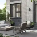 Private backyard patio rendering at Northshore Towns, featuring an outdoor living room layout with a grey sectional sofa, matching armchairs, a low coffee table, and sliding glass door access to the townhouse.