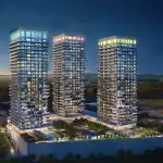 Nighttime architectural rendering of the three Thompson Towers high-rise condominium buildings with illuminated windows, glowing rooftop tiers, and an expansive podium featuring outdoor amenities and greenery.