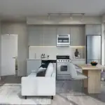 Modern open-concept kitchen and living area at Thompson Towers featuring light wood flooring, stainless steel appliances, grey cabinetry, a white sofa, and a dining table by floor-to-ceiling windows.