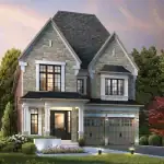 Exterior view of a classic stone-clad luxury home at King's Calling featuring a prominent gabled roof, black-framed windows, and a landscaped front entrance with evening accent lighting.