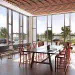 Sun-drenched co-working space at The Kith Condominiums with long communal tables, individual desks, and floor-to-ceiling windows.