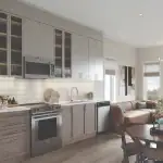 Modern kitchen and living area at Arbor West Brampton showcasing stainless steel appliances, custom cabinetry, hardwood flooring, and a cozy dining nook in an airy, sunlit layout.