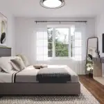 Modern primary bedroom interior in a Great Gulf Whitby Meadows home, featuring a large window for natural light, dark hardwood floors, contemporary furniture, and neutral-toned decor.