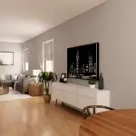 Spacious living room interior at Creekside Trail featuring a grey sectional sofa, light wood flooring, a white media console with a large city skyline art piece, and natural light from large windows.