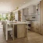 Modern open-concept luxury kitchen interior at The Winston Collection featuring light wood cabinetry, a large waterfall island with seating, high-end appliances, and matching hardwood flooring.