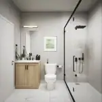 Contemporary bathroom design at Townhomes of Little Rouge including a glass-enclosed walk-in shower with black hardware, a light wood vanity, and white marble floor tiles.