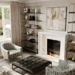 Contemporary living room interior at Erin Glen townhomes showcasing a white marble fireplace, built-in shelving, stylish accent chairs, and a large window overlooking a backyard patio.