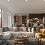 Interior view of a Wild Indigo townhome featuring a ribbed white sectional sofa, dark wood kitchen cabinetry with a marble backsplash, and large windows overlooking a backyard.