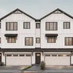 Architectural facade rendering of the Jade townhome series at Marquis Meadows, highlighting three-story white board-and-batten townhouses with integrated two-car garages and elegant dark trim.