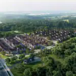 High-angle aerial view of the Riverview South Oakville residential community nestled alongside a lush green forest and walking trails, showing the organized layout of modern townhomes and detached houses.