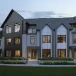 Exterior view of modern luxury townhomes at Riverview South Oakville showcasing contemporary architecture with grey brick, dark metal siding, large windows, and professionally landscaped front yards at dusk.