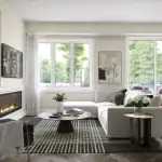 Modern living room design at Creekview Collective in Milton with herringbone hardwood floors, a built-in fireplace, large windows, and contemporary wall molding.