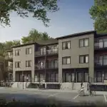 Exterior view of modern stacked townhouses at 77 McQueen, Fergus, showcasing contemporary grey paneling, wood siding accents, private glass-railing balconies, and dedicated parking spaces in a tree-lined setting.