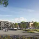 Daytime streetscape of 77 McQueen in Fergus, showing modern grey and wood-accented townhouses surrounding a central green space with wooden pergolas, bicycle paths, and lush garden borders.