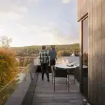 A family enjoying the sunset from a glass-railed balcony of a Calabogie Peaks townhome overlooking the autumn forest and resort lodge.