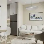 Bright, contemporary living room interior at Warbler Place Welland with a neutral color palette, cozy white sofa, minimalist decor, and a view into the kitchen.