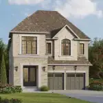 Exterior view of a luxury two-story single-family home at Heartwood Village showcasing a light grey stone and brick facade, a double-car garage, and large windows under a multi-gabled roof.
