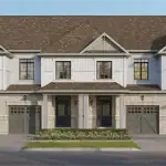 Heartwood Village - Towns 2 Front elevation of Heartwood Village townhouses showcasing a light-colored stone and white siding aesthetic with gabled roofs and carriage-style garage doors.