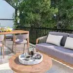 Private outdoor terrace at Sol Stacked Towns featuring a modern patio sofa, a wood dining table with a BBQ grill, and lush greenery providing a serene urban retreat.