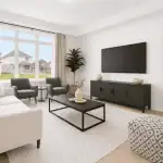 Bright and airy living room interior at West Community showing a neutral white sofa, dark wood media console, large windows with natural light, and contemporary minimalist decor.