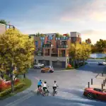 Street-level rendering of the Jefferson Heights community neighborhood, showing a brick and stone townhouse street with residents cycling, walking, and driving on a paved road next to landscaped trees and a nearby pond.
