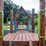 Wooden playground construction with green handrails in a Londrina park surrounded by nature.