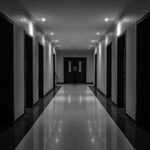 Schwarzweisser Korridor als Sinnbild für lineares Denken, glatte KI-Oberflächen und verdeckte strukturelle Risiken in Unternehmen