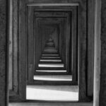 Visuelle Darstellung einer Echokammer: Eine endlose Flucht aus Betonrahmen, die den Tunnelblick und die ständige Selbstbestätigung im Vertrieb symbolisiert.