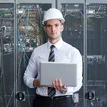 Engineer holding a laptop while inspecting technology