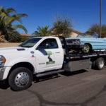Freeway Towing & Storage flatbed truck towing a classic 1964 Chevy Impala convertible in Phoenix, AZ