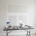 Handyman repairing drywall with tools and patch on wall