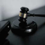 Close-up of a wooden judge's gavel resting on its base against a dark background.