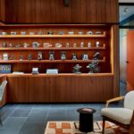 Walnut-paneled study with built-in shelving, a desk, a cream lounge chair and a patterned rug