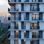 Contemporary residential apartment building with modern balconies and floor-to-ceiling windows.
