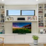 Custom made Entertainment unit with free floated shelf and bookcase each side. This unit has solf close push touch doors and finshed in white satin ploy. Custom made joinery and cabinet making.
