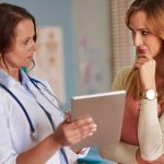 Médica morando um exame para a paciente e explicando se quem tem hipotireoidismo pode engravidar.