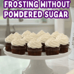 A wide shot of a white kitchen island featuring a platter of chocolate cupcakes with vanilla frosting swirls and a professional stand mixer in the background.