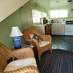 A cozy living area with wicker furniture and a view of the kitchen in a charming Eureka Springs home.
